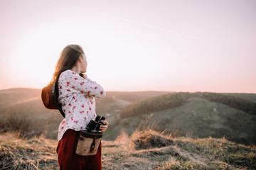 Portrait of a attractive young girl with a hat in the mountains at sunset. She resting and sitting wearing stylish fall outfit. Concept travel