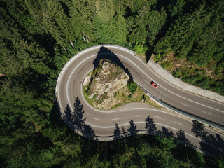 aerial view of road going around rock in forest