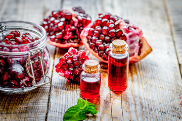 sliced pomegranate and extract in glass on wooden background