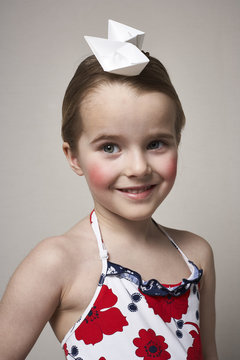 Portrait of smiling little girl with two paper boats on her head
