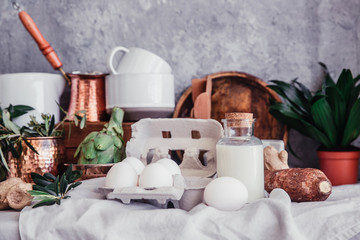Still life in Rustic style fresh eggs, milk, artichoke on linen table. Organic eco farm products