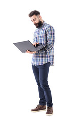 Young modern handsome bearded worker holding and using laptop computer. Full body isolated on white...