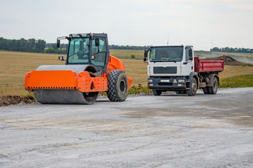 Obraz premium Asphalt roller and little truck take a break