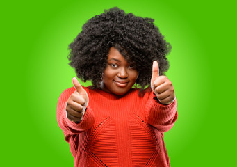 Beautiful african woman stand happy and positive with thumbs up approving with a big smile expressing okay gesture