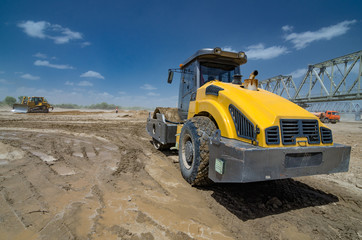 Fototapeta premium Roller on earthworks on the background of construction