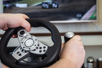 playing in the race behind the wheel of a game console in front of the big screen
