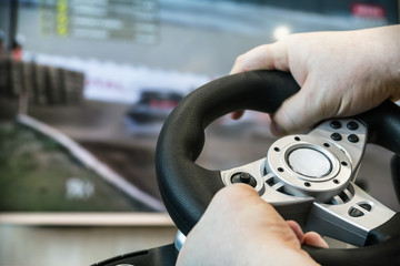 playing in the race behind the wheel of a game console in front of the big screen