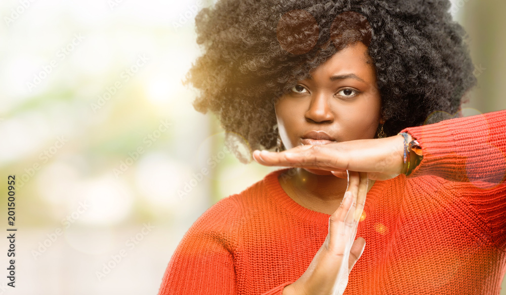 Poster Beautiful african woman serious making a time out gesture with hands, outdoor