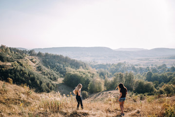 Obraz premium Beautiful young girls walk on autumn mountain slopes, fun, jump. female friendship