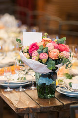 arrangement, interior decor, party concept. on the coner of old wooden table served for reception there is a wonderful bouquet composed of bright pink roses and puffy peonies of pastel light coloures