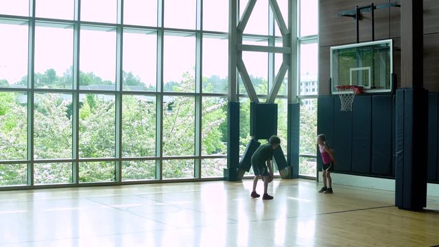 Two children playing basketball in a gym