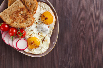 Healthy simple breakfast with bread toast, fried eggs and vegetables