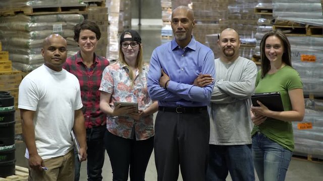 Male and female work team, standing in a row, smiling at camera.