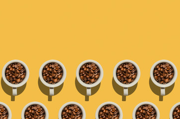 Cup concept. White cups with coffee beans on yellow background.  Creative style.