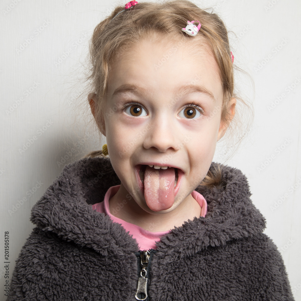 Wall mural Happy little girl showing her tongue.