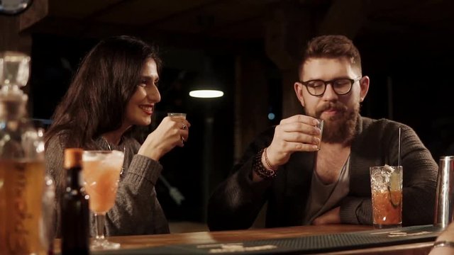 Man and woman spend time in a bar drinking shots together. Friends enjoying company of each other.