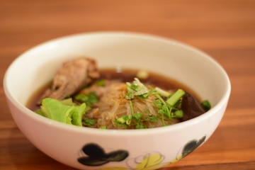 Close up Braised chicken noodle soup on wooden table ready to eat