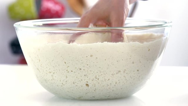 Yeast dough squeeze with handOn the table is a transparent bowl with dough. Yeast dough squeeze with hand