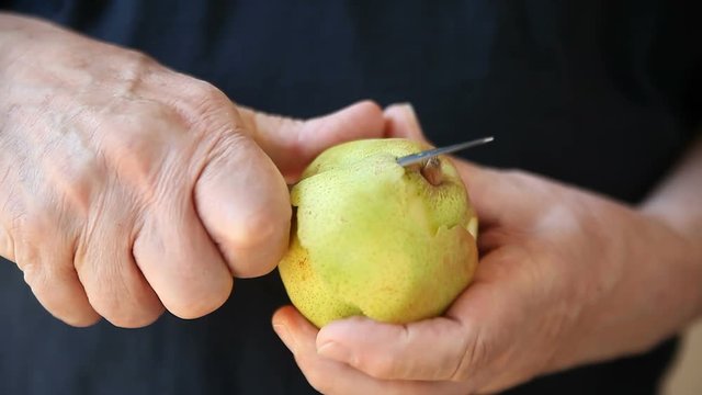 Older man removes peel from a fresh pear