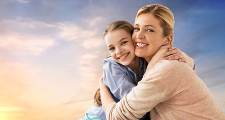 Fototapeta premium people and family concept - happy smiling mother hugging daughter over evening sky background