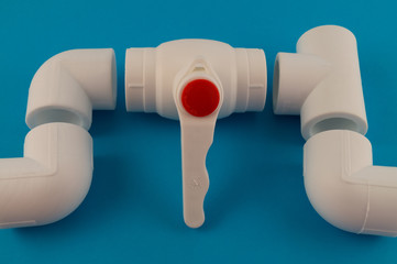 Fittings for the installation of water pipes - a faucet, tee, three corners of white plastic, an example of a connecting unit when creating a water supply system of PVC pipes.