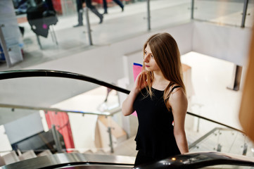 Girl with shopping bags in the mall at the escalator.