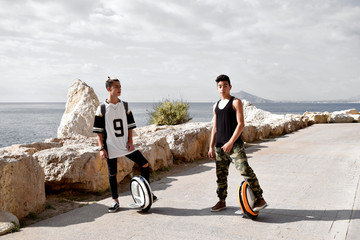 Dos jóvenes están paseando en mono ruedas eléctricas en el hermoso parque natural del Peñón de Ifach en la costa mediterránea de Costa Blanca en España