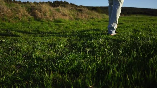 Hombre joven caminando descalzo por la hierba 