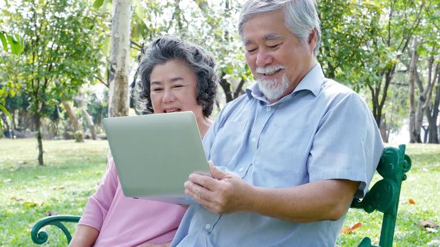 Asian couple elder people relax at park together. Elder people using laptop with happy emotion. People lifestyle concept 