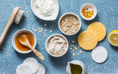 Homemade beauty products concept. Natural moisturizing, nourishing, cleansing face mask - coconut oil, oatmeal, natural yogurt, vitamin E, honey, face brush, sponge on blue background, top view