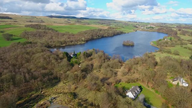 Ascending aerial footage of Banton Loch near Kilsyth in Scotland. Panorama of the loch, Kilsyth Hills and woodland.