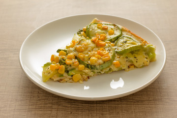 Slice of pizza: Toppings are zucchini, corn kernels and mozzarella cheese. Wooden table. Detail of meal, closeup, selective focus.