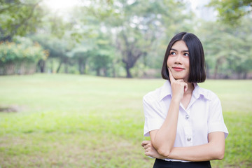 Portrait of asian woman smile and look up with copy space. Happy asian beautiful teenage girl having good time in the park. Education back to school spring summer concept.