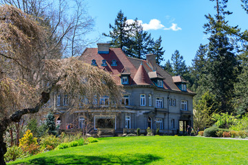 Pittock Mansion, view on the house surrounded by trees from the garden on a beautiful sunny spring day, Portland