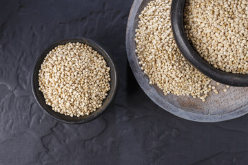 Quinoa grains with spoon and bowl on black background