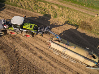 Aerial view of modern Tractor with liquid manure on the agricultural field - prepares it for sowing -  set of equipment for making liquid fertilizer into the soil in the agricultural field 