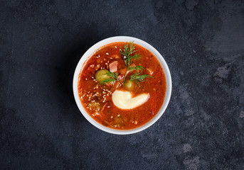 Tomato soup with meat, olives, herbs in white bowl, black bread. Solyanka