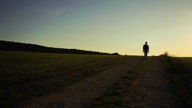 Hombre dando un paseo por un camino al atardecer 