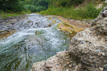 Naklejka na ściany i meble Mountain river flowing through the green forest