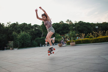 Young sporty woman riding on the longboard in the park