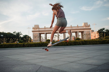 Young sporty woman riding on the longboard in the park © primipil