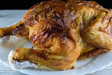 fried chicken whole, on a white plate on a wooden background