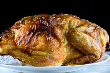 fried chicken whole, on a white plate on a wooden background