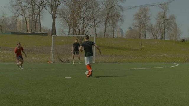 Skillful defender making sliding tackle and winning soccer ball back from stricker during football match. Young footballer making a slide tackle to knock the ball away in the pitch. Stabilized shot.