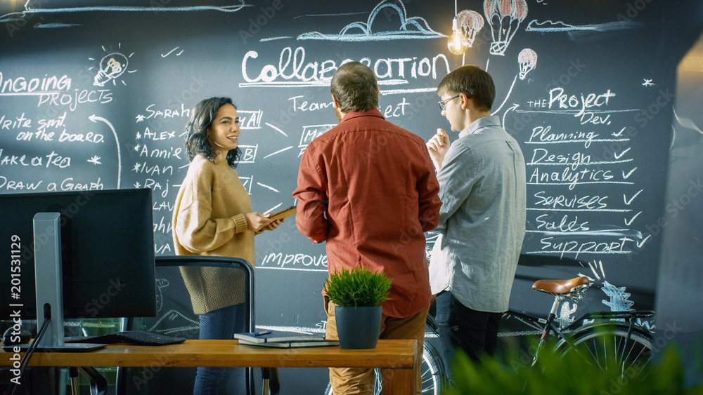 Poster Female Developer with Tablet Computer Talks With Programer and Project Manager, They use Blackboard Wall as a Planner. They Work in the Stylish Creative Office.