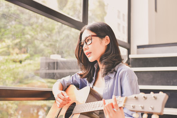 Music Concepts. Asian girls playing guitar. Asian women relaxing with music. Asian women have a...