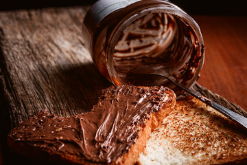 Empty can of chocolate paste with a spoon inside and bitten toast bread with chocolate paste spread on it