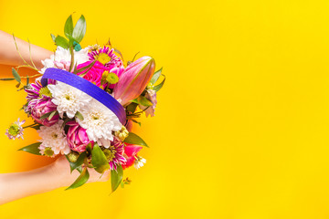 Woman hands pass bouquet, yellow background, copy space