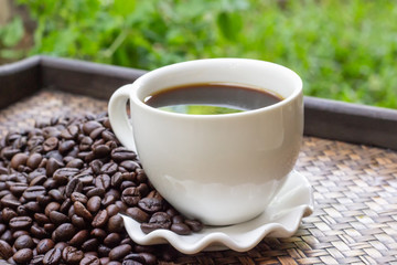 White coffee cup with coffee beans placed on a tray.