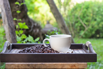 White coffee cup with coffee beans placed on a tray.